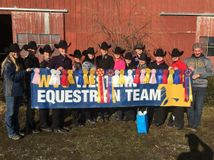 group picture of team standing behind WVU Western Equestrian Team banner